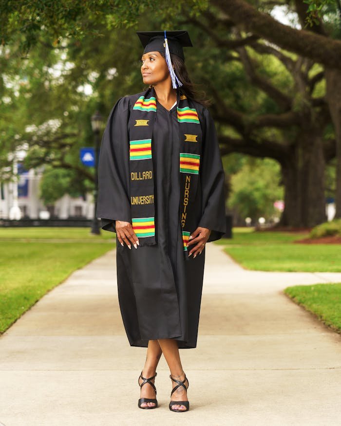Proud Dillard University nursing graduate posing in cap and gown outdoors.